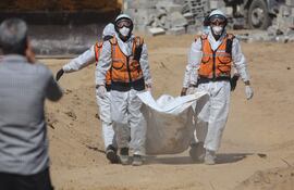 Miembros de la Defensa Civil palestina llevan un cadáver a un cementerio en Deir el Balah, en la zona central de la Franja de Gaza.