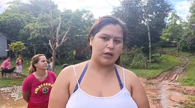 Sandra Cuenca en blusa blanca conversa con otra mujer en camisón rosado, rodeadas de vegetación en un entorno rural.