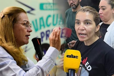 María Teresa Barán con camisa clara y gesticulando, y Rossana González en vestimenta oscura, hablando intensamente en un evento interior, con cartel de 'VACUNA' detrás.