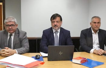 Óscar Boidanich con camisa blanca y blazer oscuro, Claudio Lovera con traje oscuro, y César Alfonso en reunión con documentos y laptop.