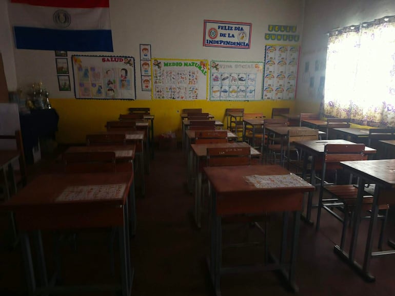 Aula vacía con escritorios organizados, cartel de 'FELIZ DÍA DE LA INDEPENDENCIA', luz suave entrando por la ventana.