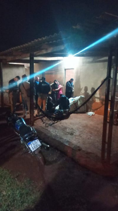 Varios policías conversan en la noche, con una persona consolando a otra en un ambiente tenso cerca de una casa sencilla.