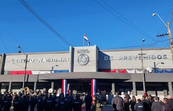 Multitud de personas, principalmente uniformadas, en ceremonia con banderas nacionales ondeando en el Centro Nacional de Prevención.