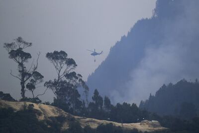 Un helicóptero combate hoy un incendio forestal en el cerro El Cable, en Bogotá (Colombia).