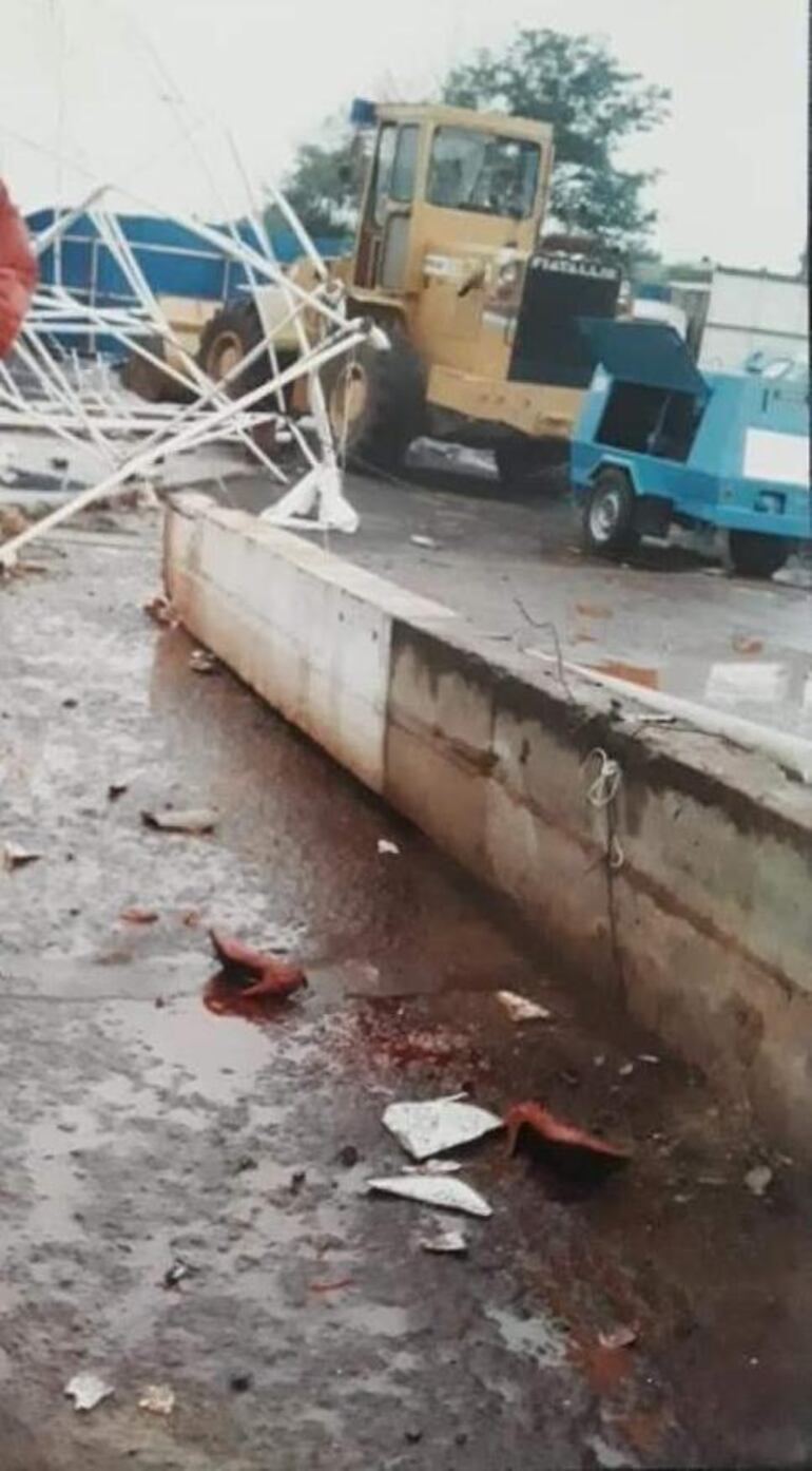 Una de las columnas mortíferas del tinglado colapsado. A lado los calzados de una víctima y atrás un tractor en la tarea de búsqueda de cuerpos.
