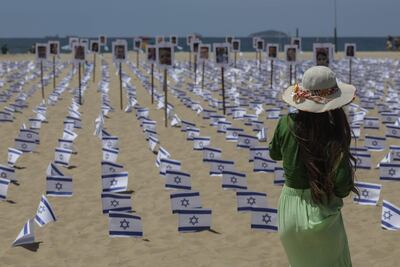Una mujer observa banderas israelíes y fotografías dispuestas en la playa de Copacabana por parte de la ONG Río de Paz que simbolizan a las víctimas del ataque de Hamás del pasado 7 de octubre, hoy, en Río de Janeiro (Brasil).