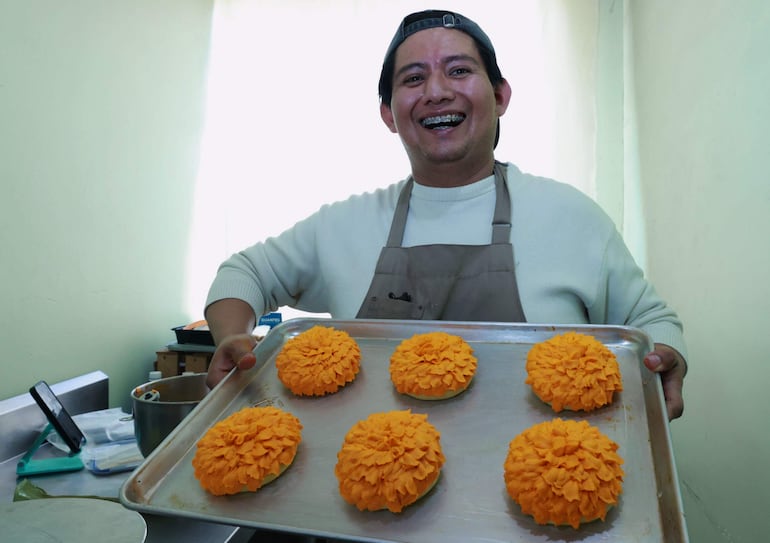 El repostero Jonathan Barrera posa con alimentos en forma de flor de cempasúchil, en Ciudad de México (México).