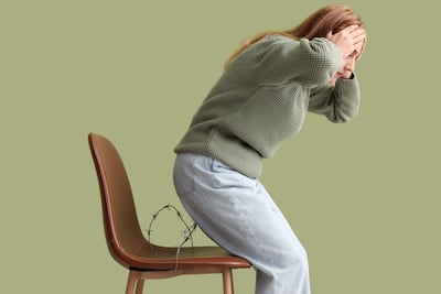 Mujer con dolor al sentarse, concepto de hemorroides.