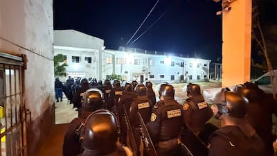 Grupo de policías alineados, equipados con cascos y escudos, en un ambiente de alta seguridad, listos para operar.
