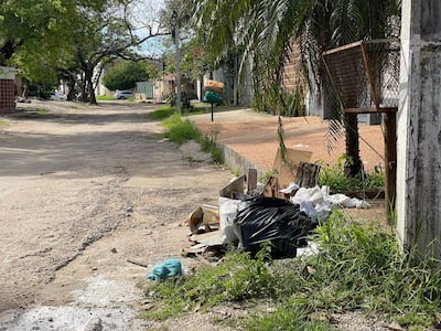 Calle semi-abandonada en el barrio Itay, con residuos y vegetación a los costados.