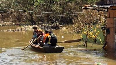 Cuatro niños en canoa; uno rema, otro viste camiseta oscura, otro tiene gorra naranja, y el cuarto lleva chaleco reflectante.