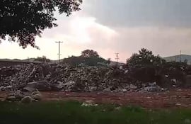 Montículo de basura en un paisaje sombrío. El cielo nublado sugiere un ambiente degradado.
