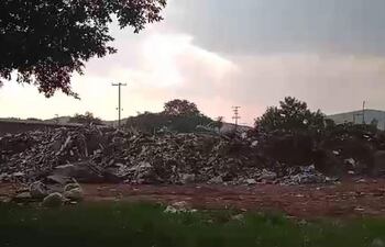 Montículo de basura en un paisaje sombrío. El cielo nublado sugiere un ambiente degradado.