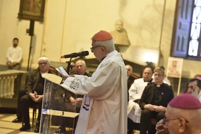Cardenal Vicenzo Turturro en vestimenta blanca y birrete rojo, hablando ante un micrófono rodeado de clérigos atentos.