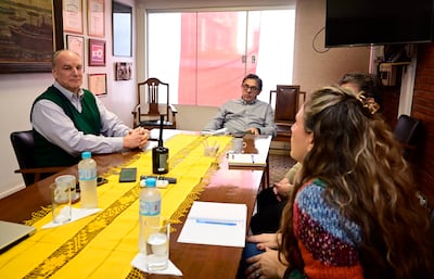 Brady North Zazolilla en chaleco verde habla con su equipo, mientras una mujer con suéter colorido y otro hombre escuchan atentamente.