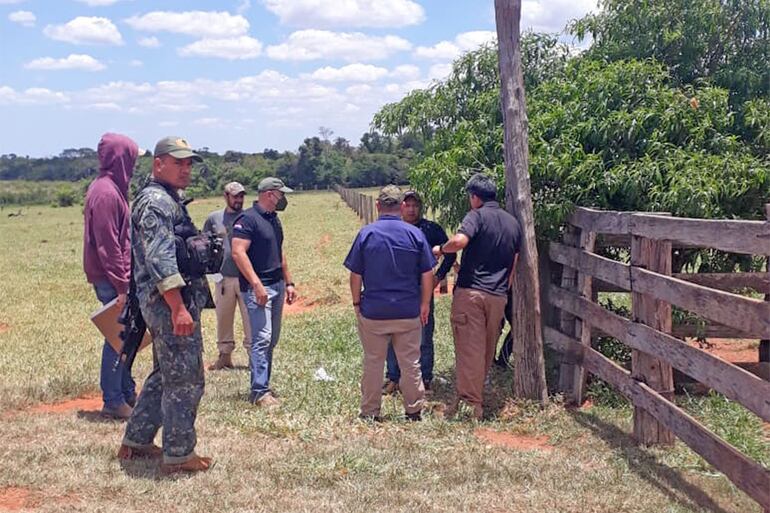 El fiscal Antisecuestro, Lorenzo Lezcano (remera negra, con quepis); el director de Investigación de Hechos Punibles de la Policía, comisario principal César Silguero (con camisa azul, de espaldas), y el subjefe del departamento Antisecuestro de la Policía, comisario Mario Vallejos (remera negra, de espaldas), entre otros, en el portón de la estancia Guyra Campana donde fue secuestrado el menonita Peter Reimer.