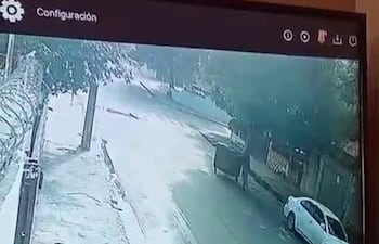 Calle vacía con superficie pavimentada y acera, un vehículo blanco y otro oscuro estacionados.