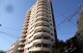 Edificio alto con terrazas y balcones en un entorno urbano sin personas visibles, bajo un cielo despejado.