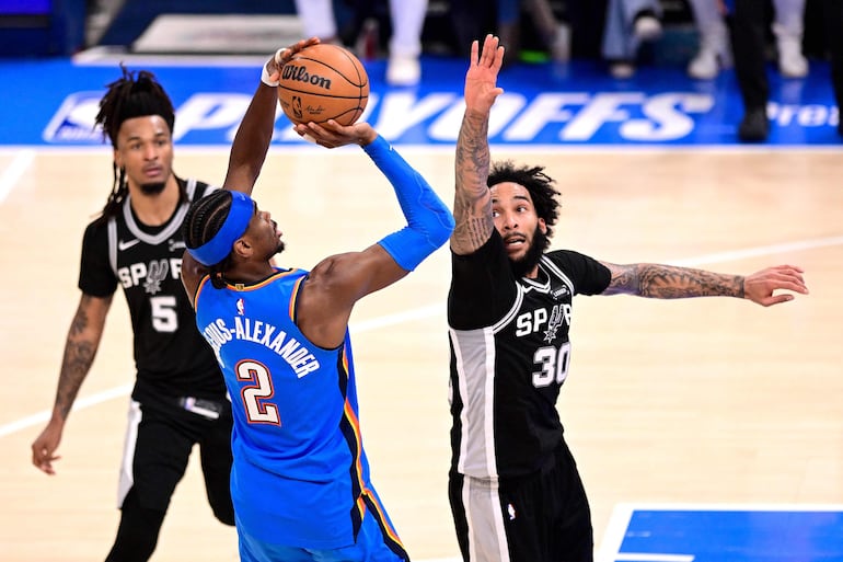 Julian Champagnie de San Antonio Spurs intenta defender a Shai Gilgeous-Alexander de Oklahoma City Thunder.