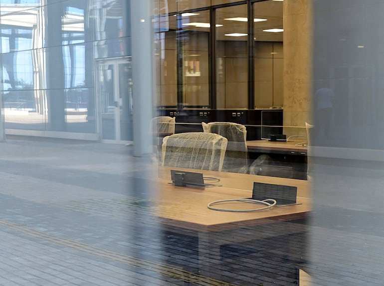 Oficina moderna con sillas apiladas y mesa amplia, iluminada por amplias ventanas que permiten el ingreso de luz natural.
