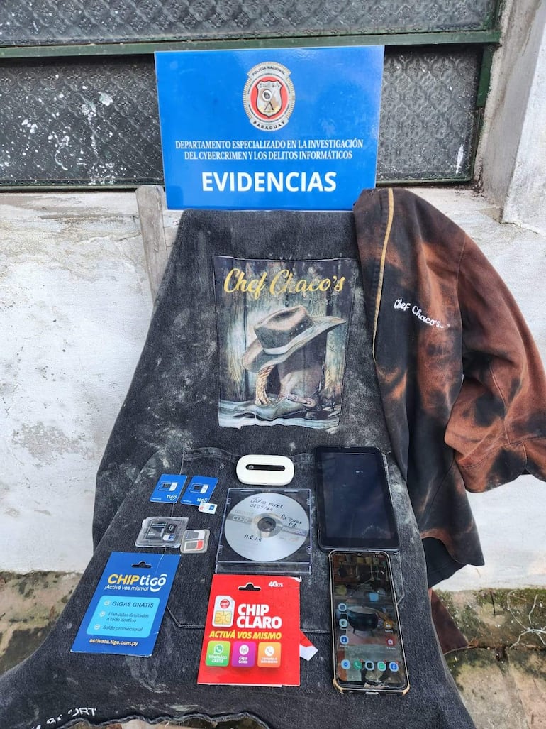 Mesa con evidencias de telecomunicaciones, incluyendo documentos, tarjetas SIM y un disco compacto en ambiente informal.