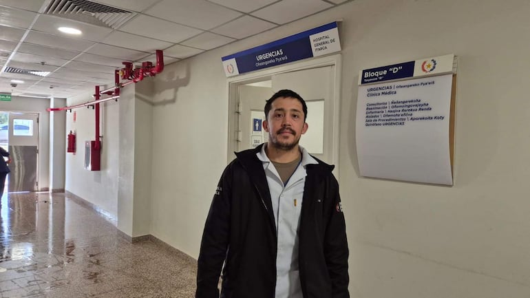 Sergio Medina, hombre vestido con chaqueta oscura y camiseta blanca, mira hacia la cámara en el hospital mientras se aprecia un entorno de urgencias.