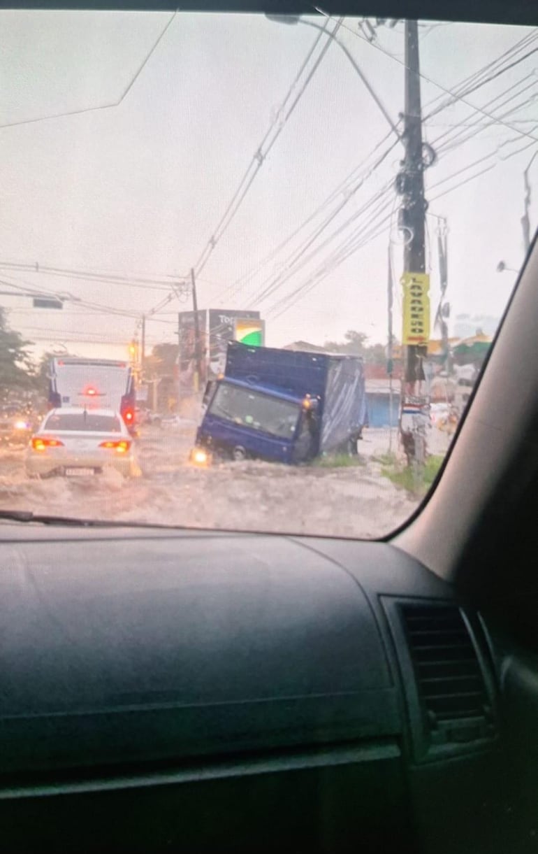 Mientras otros vehículos pasan lentamente por el raudal, un camión quedó varado. 