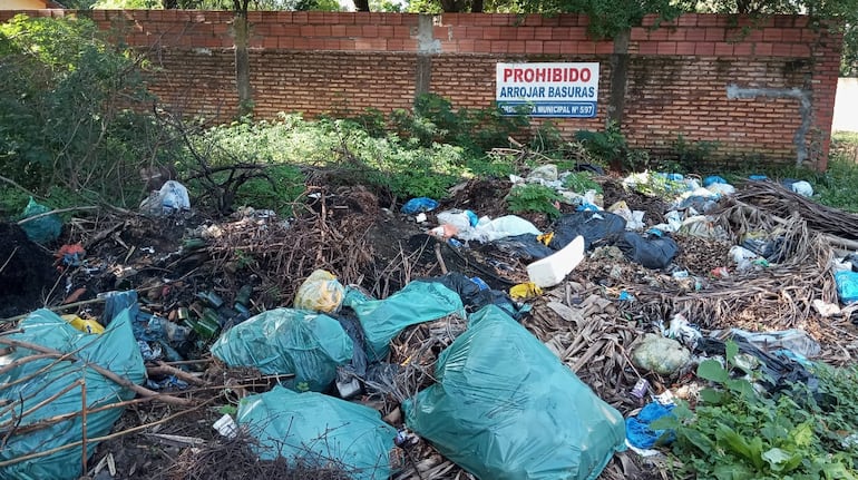 Terreno de acumulación de desechos donde se ve un cartel que dice: Prohibido arrojar basuras.