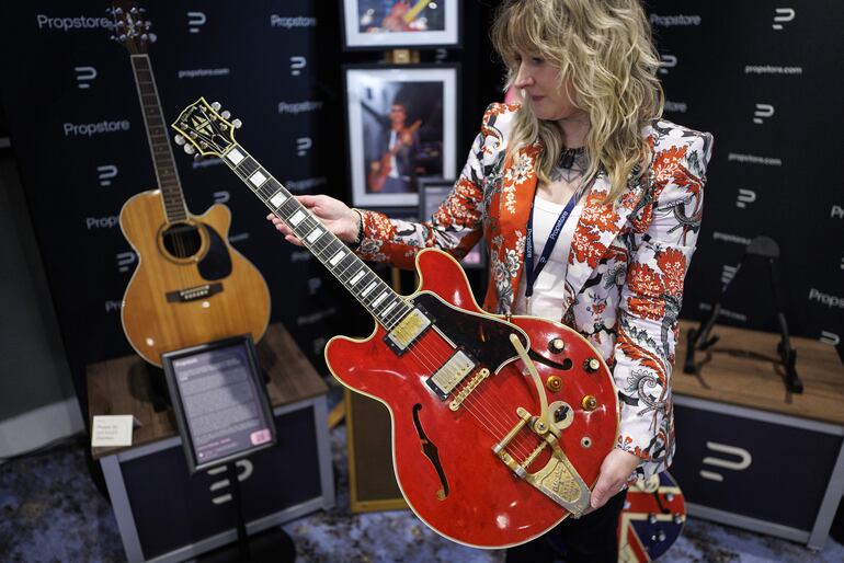 Una persona de la galería exhibe la guitarra, que fue subastada junto a otros artículos que pertenecieron a figuras de la música.