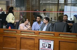 Luis Fernando Bernal en blusa amarilla habla en recinto legislativo, mientras Pablo Callizo escucha atentamente con gesto serio.