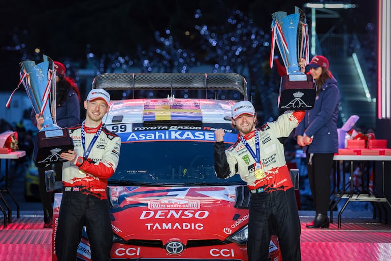 Oliver Solberg (derecha) y Elliott Edmondson festejan con sus respectivos trofeos frente al Toyota GR Yaris Rally1.