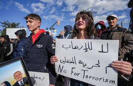 Una mujer sostiene una pancarta con la leyenda en árabe "No al terrorismo, sí a la libertad de los detenidos" mientras miembros de la comunidad alauita se reúnen para protestar contra la violencia contra los alauitas tras el atentado con bomba en la mezquita de Homs, en la ciudad de Latakia, Siria.