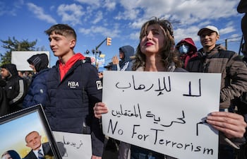 Una mujer sostiene una pancarta con la leyenda en árabe "No al terrorismo, sí a la libertad de los detenidos" mientras miembros de la comunidad alauita se reúnen para protestar contra la violencia contra los alauitas tras el atentado con bomba en la mezquita de Homs, en la ciudad de Latakia, Siria.
