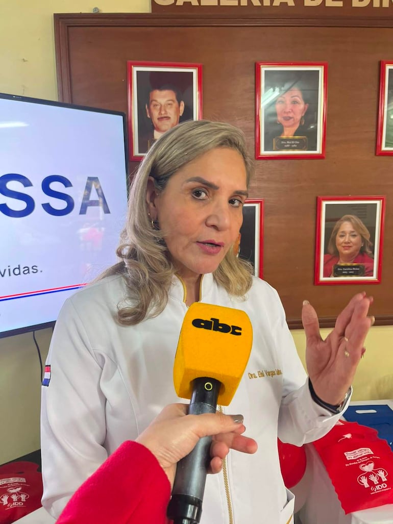 Dra. Elsi Vargas Saina, con abrigo blanco y micrófono amarillo, habla en un evento decorado en el Censsa.