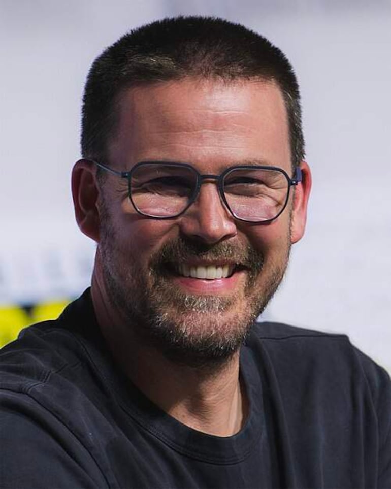 Zach Cregger sonríe con gafas y camiseta negra, en un ambiente informal, posiblemente un evento de cine.