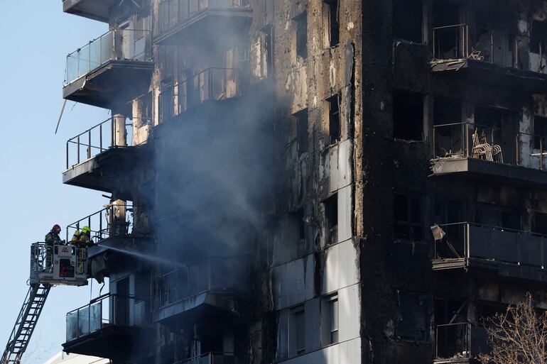 Los bomberos enfrían el complejo residencial, luego de apagar las llamas. 