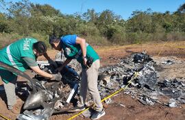 Funcionarios de Dinac revisan los restos del avión quemado en Tavaí.