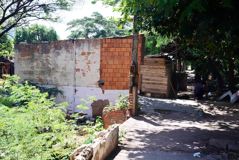 Entorno urbano con viviendas de ladrillo y madera rodeadas de vegetación en un camino de tierra.