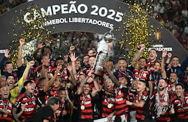 El capitán de Flamengo, Bruno Henrique (D), y el uruguayo, Giorgian de Arrascaeta (I), levantan el trofeo con sus compañeros de equipo después de ganar el partido final de la Copa Libertadores entre Palmeiras y Flamengo en el estadio Monumental, en Lima.