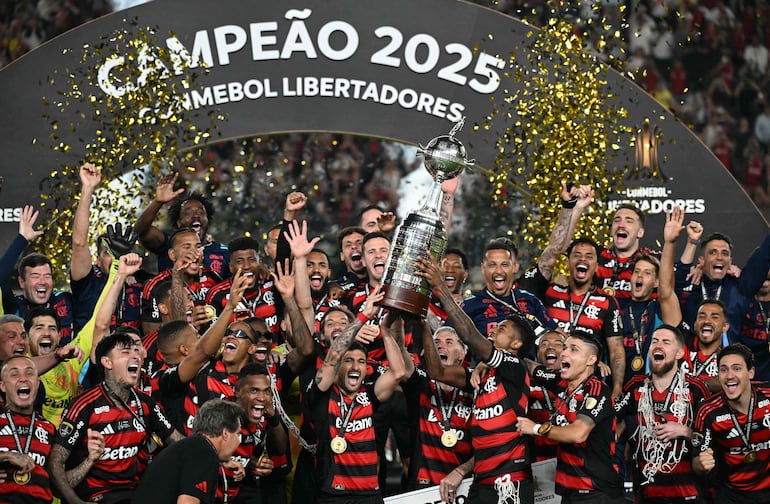 El delantero del Flamengo, Bruno Henrique, y el centrocampista uruguayo Giorgian de Arrascaeta levantan el trofeo con sus compañeros tras ganar la final brasileña de la Copa Libertadores entre Palmeiras y Flamengo en el Estadio Monumental "U" Marathon en Lima.