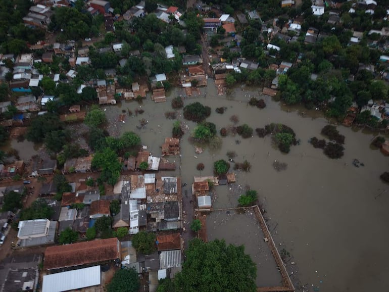 Vista aérea del barrio San Rafael con casas de techos terracota parcialmente sumergidas en agua, rodeadas de vegetación.