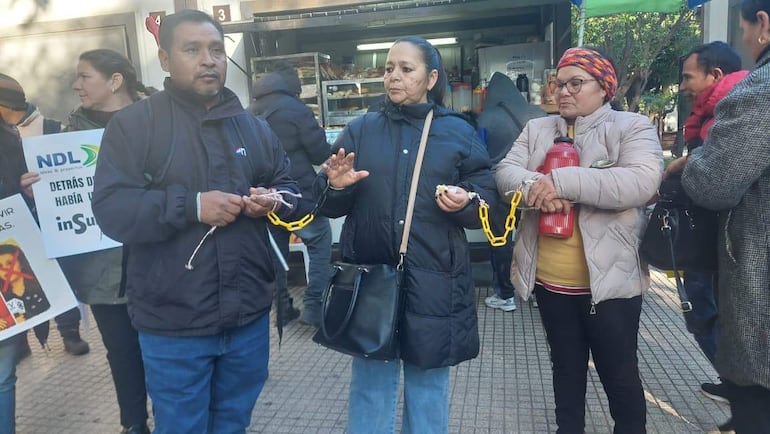 Pedro Coronel con cadenas en mano junto a tres personas, expresando resistencia y unidad en una protesta bajo un clima fresco.