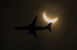 Imagen ilustrativa: un avión sobrevuela la trayectoria de un eclipse solar parcial, visto desde Glen Rock el 8 de abril de 2024 en EE.UU.