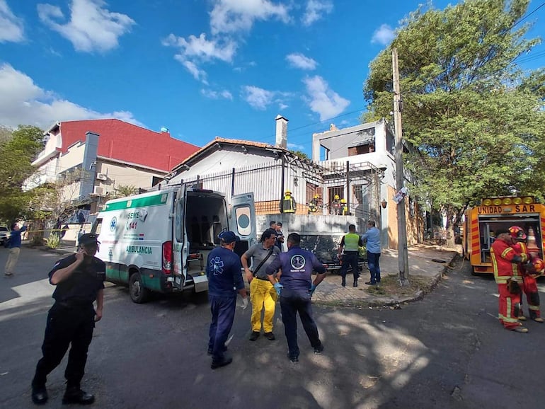 Hombres en uniforme de policía y bomberos en la escena del derrumbe, trabajando en medio de un día soleado.