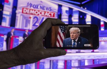 Un espectador sigue en su teléfono móvil el primer debate presidencial republicano en directo por Fox News y la entrevista de Tucker Carlson al entonces candidato Donald Trump en la plataforma 'X', en Los Ángeles, California (EE. UU.), el 23 de agosto de 2023.