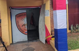 Exterior de un cuartel con emblema visible, paredes amarillas y decoración festiva en un ambiente conmemorativo.