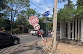 Un cartel de PARE inclinado en la vereda de la calle Zanotti Cavazzoni, que también registra una aparente pérdida de agua.