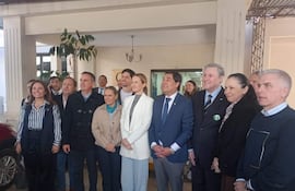 Grupo de personas sonrientes en atuendos formales, posando en un ambiente interior amigable durante un evento político.