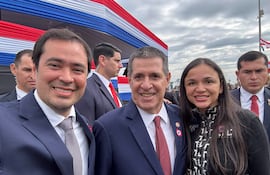Rodrigo Gamarra y Jazmín Narvaez sonríen en eventos patrios, con fondo decorado en rojo, blanco y azul.