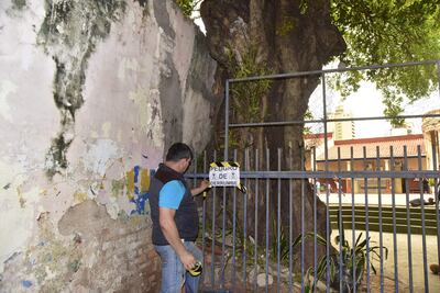 Personal de la escuela República Argentina coloca un cartel de advertencia cerca dela muralla que está en riesgo de derrumbe.